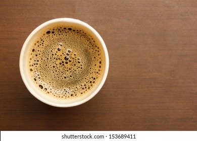 Top View Of A Paper Cup Of Black Coffee On Wooden Table