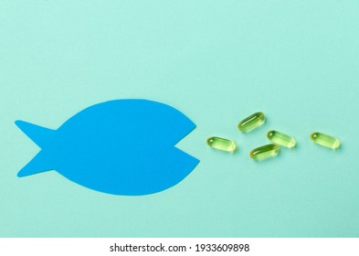 Top View Of Paper Fish Shape And Capsules Of Omega 3 Vitamins On The Bright Blue Surface.Empty Space