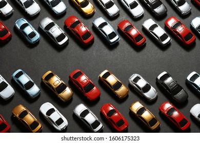 Top View Of Parked Toy Cars On A Black Background Like A Car Parking Lot.