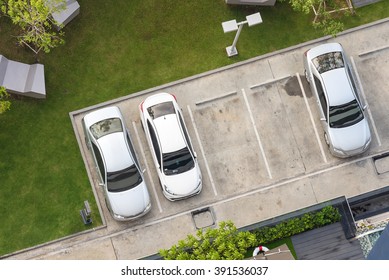 Top view of parking area with small garden in modern building 