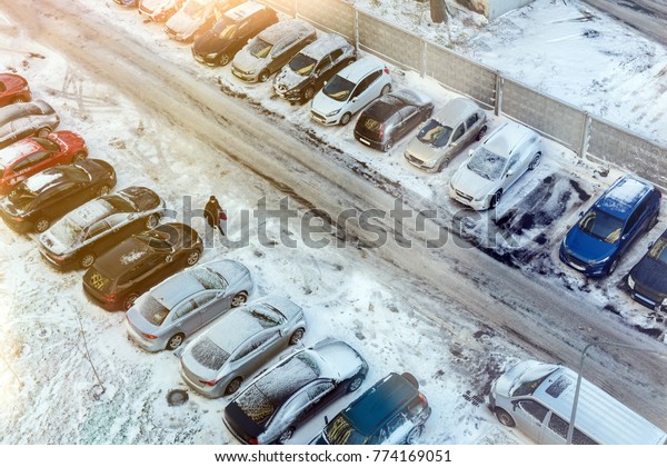 Top view of parking full of cars covered by snow\
in early winter morning.