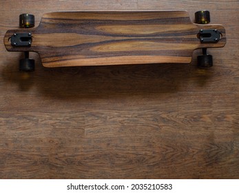 Top View To The Part Of Brown Longboard With Brown Rubber Wheels And Logo ARBOR. Dark Mood.