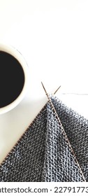 top view of partial tea cup and knitting project in progress of grey yarn