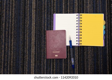 Top view passport, pen and note book on carpet background for tourist travel at the airport.Different accessory for travel.Traveler concept.