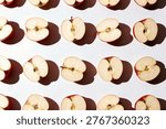 Top view of a pattern created by rows of halved red apples showing the seeds and core on a clean white background.