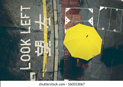 Top View Of Pedestrian Is Waiting With Yellow Umbrella On Pavement. Hong Kong, China. Umbrella Protests.