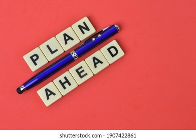 Top View Of Pen And Scrabble Letters With Text PLAN AHEAD Over Red Background. 