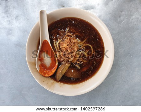 Top view Penang famous Lor Mee, it is a Penang hawker noodle soup of a gooey broth made from tapioca flour and egg, topped with pork slices, and served with chilli and vinegar garlic pastes.