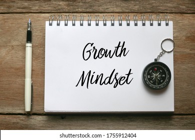 Top view of pen,compass and notebook written with Growth Mindset on wooden background.