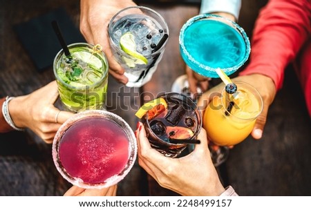 Top view of people hands toasting multicolored fancy drinks - Young friends having fun drinking cocktails at happy hour - Social gathering party concept on vivid filter - Shallow depth of field