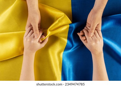top view people holding hands with-Ukrainian flag. - Shutterstock ID 2349474785