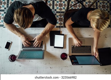 Top view of people meeting at old wooden table and working with laptops, smart-phones and touch-pads with blank empty screen for your information or content - Shutterstock ID 323566982