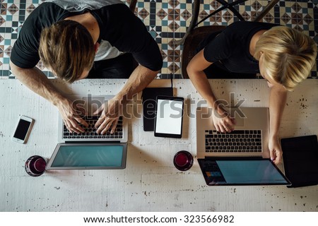 Top view of people meeting at old wooden table and working with laptops, smart-phones and touch-pads with blank empty screen for your information or content