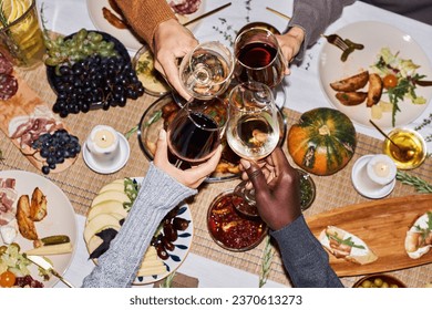 Top view of people toasting with wine glasses at festive dinner table celebrating Thanksgiving, copy space - Powered by Shutterstock