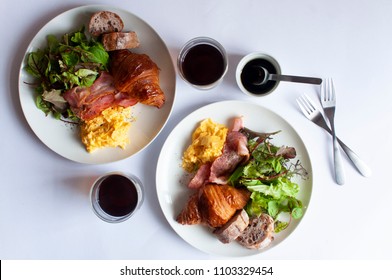 Top view of perfect table styling of Sunday brunch dish with coffee and white background.The dish includes bread, croissant, green salad, egg and bacon.