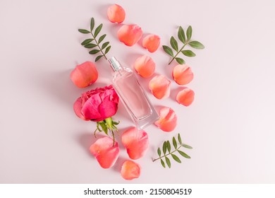 top view of the perfume product in glass flakrn against the background of rose petals and flower. pink pastel background. flat styling