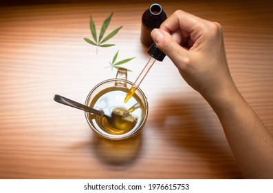 Top View Of A Person Pouring CBD Tincture Made With Marijuana In A Hot Drink.