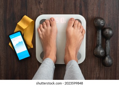Top View Of a Person Standing On a Smart Weighing Scale, a smartphone connected to the Scale and Fitness equipment. Smart technology and health care concept