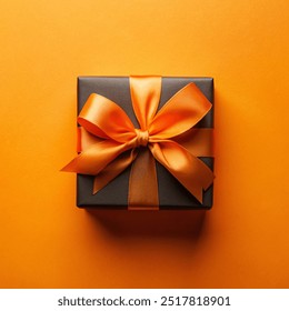 Top view photo of black giftbox with orange satin ribbon bow on isolated orange background with empty copy-space - Powered by Shutterstock