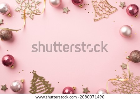 Top view photo of christmas decorations pink balls gold bell pine snowflake shaped ornaments glowing stars serpentine and sequins on isolated pastel pink background with empty space in the middle