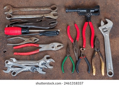 Top view photo of few old wrenches, screw drivers, vise grip, pipe wrenches and pliers on an old rusty iron workbench. All names, logos and brands were removed. Enjoy!