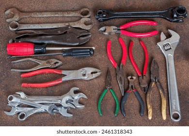 Top view photo of few old wrenches, screw drivers, vise grip, pipe wrenches and pliers on an old rusty iron workbench. All names, logos and brands were removed. Enjoy!