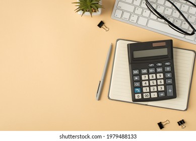 Top view photo of flowerpot glasses on keyboard calculator on grey copybook pen and binders on isolated beige background with copyspace - Shutterstock ID 1979488133