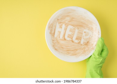 Top View Photo Of Hand In Green Rubber Glove Holding Dirty Dish With Inscription Help On Isolated Yellow Background With Copyspace