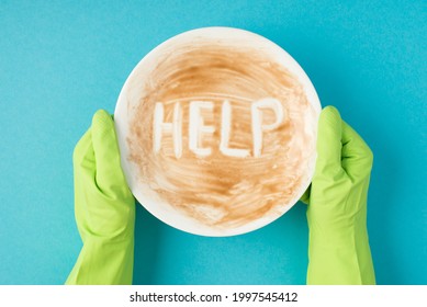 Top View Photo Of Hands In Green Rubber Gloves Holding Dirty Dish With Inscription Help On Isolated Pastel Blue Background