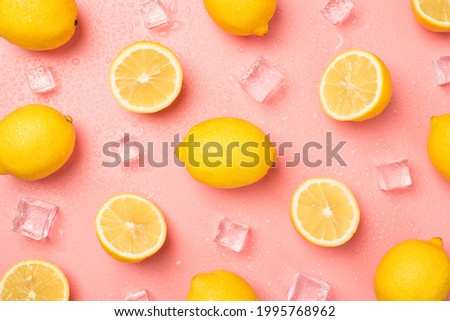 Top view photo of ice cubes water drops halves and whole yellow lemons on isolated pastel pink background