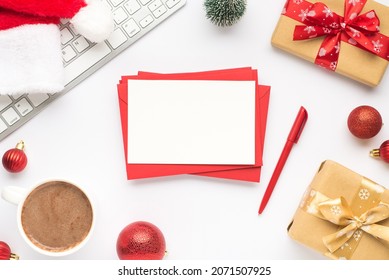 Top view photo of keyboard cup of hot drinking santa claus hat pine toy red christmas tree balls gift boxes stack of red envelopes paper sheet and pen on isolated white background with copyspace - Powered by Shutterstock