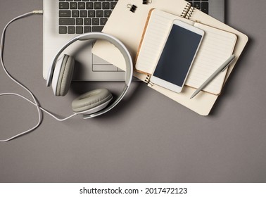 Top view photo of laptop keyboard wired white headset grey pen and mobile phone on two open organizers on isolated grey background with copyspace