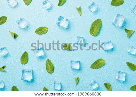 Top view photo of mint leaves ice cubes and water drops on isolated pastel blue background