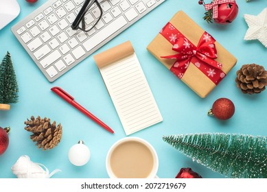 Top view photo of notebook pen glasses keyboard mouse cup of hot drinking pine toys christmas tree balls star cones bell spools of ribbon giftbox on isolated pastel blue background with empty space
