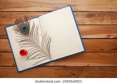 Top view photo of opened Diary, red fabric color and a Peacock Feather over it on wooden background. Flat lay image of blank diary. Stock Photo