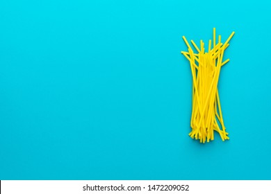 Top view photo of pile of yellow drinking straws over turquoise blue background with copy space. Flat lay image of many plastic bendy cocktail straws with left side composition.