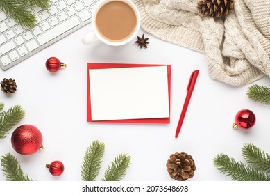 Top view photo of red envelope paper sheet pen keyboard cup of hot drinking red christmas tree balls pine twigs cones anise and cozy sweater on isolated white background with copyspace
