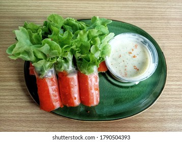 Top view photo of rolls salad with lettuce leaves, sliced carrots, crab sticks and ebiko eaten with wasabi-mayonnaise, healthy food.