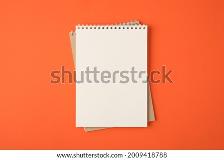 Top view photo of spiral notebooks on isolated vivid orange background with blank space