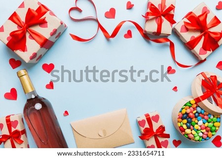 top view photo of st valentine day decor shopping, bag, wine, bottle, envelope, gift, box, candy and red heart on colored background with empty space. Frame background.
