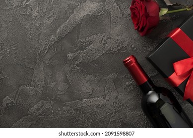 Top view photo of valentine's day decorations wine bottle black giftbox with red bow and red rose on isolated textured dark grey concrete background with blank space - Powered by Shutterstock