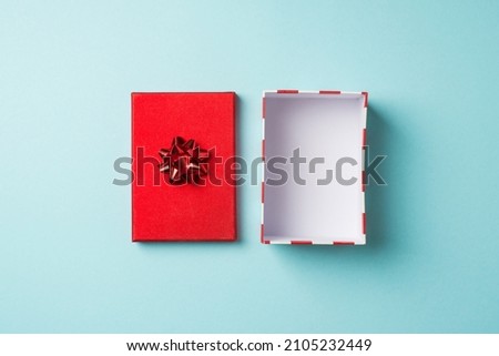 Top view photo of valentine's day decorations open empty giftbox with red lid and star bow on isolated pastel blue background with copyspace