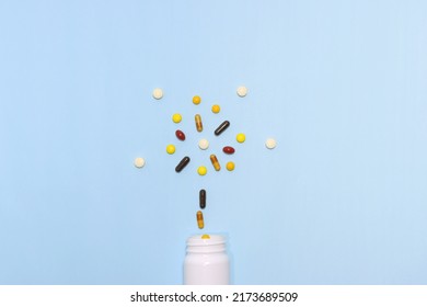 Top View Photo Of Vitamins And Supplements On Blue Background With A White Bottle. Including Multi Vitamins, Vitamin B, Vitamin C, Vitamin D, Collagen Tablets, Probiotics Capsules And Iron Capsules.