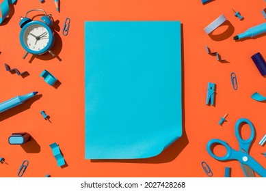 Top view photo of vivid blue sheet of paper with curled corner and school supplies blue stationery on isolated orange background with blank space