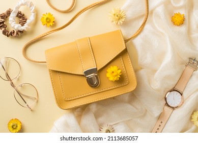 Top view photo of woman's day composition yellow leather handbag stylish glasses scrunchies golden wrist watch and field flowers on isolated beige background