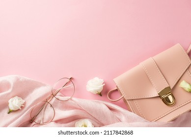 Top view photo of woman's day composition pink leather handbag soft textile stylish glasses and white prairie gentian flower buds on isolated pastel pink background with empty space