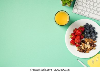 Top view photo of workplace keyboard plant sticker note paper pen glass of juice and plate with blueberries strawberries and nuts on isolated turquoise background with copyspace - Powered by Shutterstock