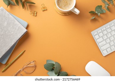 Top view photo of workstation keyboard computer mouse cup of coffee on wooden stand glasses planners gold pen binder clips and eucalyptus on isolated orange background with copyspace in the middle