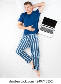 Top View Photo Of Young Man Sleeping In A Big White Bed With Laptop