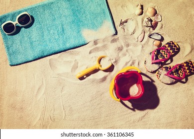 Top view photograph of sandy beach with summer accessories and copy space around objects. Horizontal photo taken from above with visible sand texture. Vintage, retro effect processing.